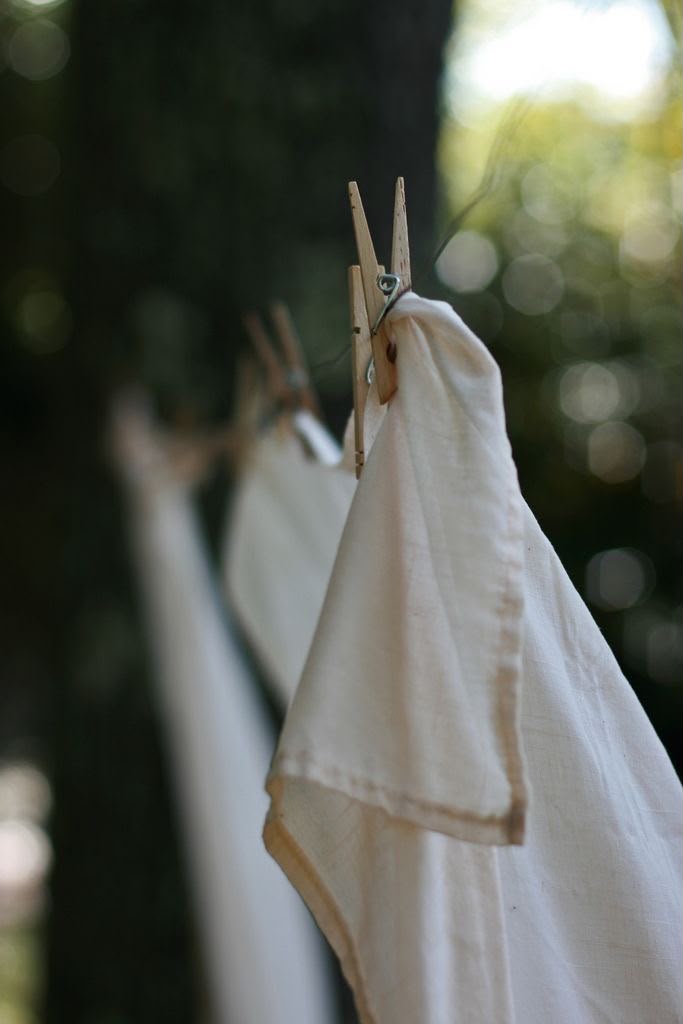 Linge blanc séchant sur un fil, pincé par des pinces en bois